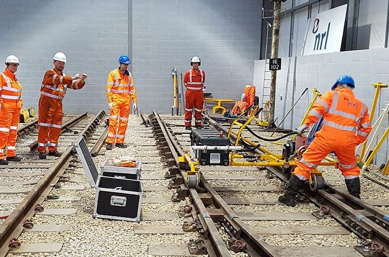 Rail workers in orange PPE use a training facility for skills development and career progression.