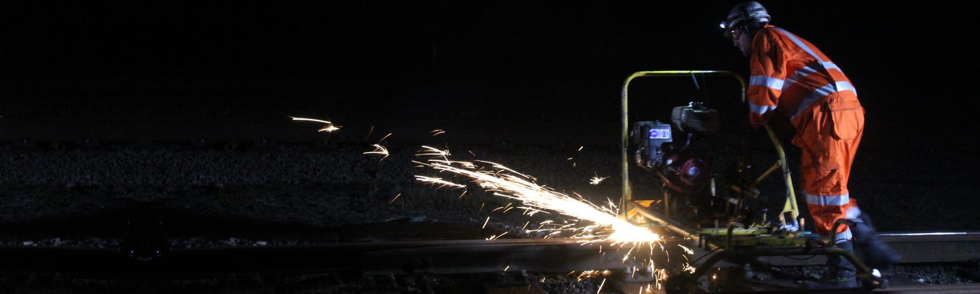 Rail worker in the dark, grinding with sparks flying