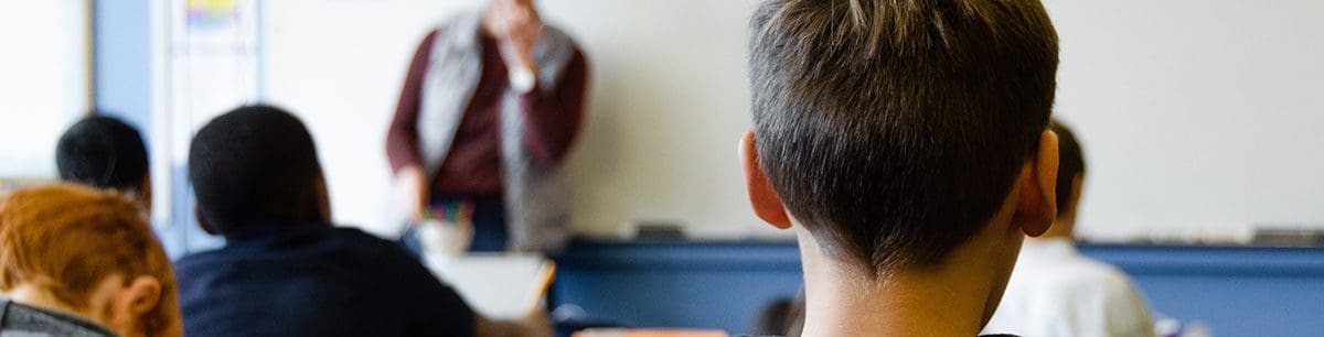 a close up of the back of a boys head in a classroom