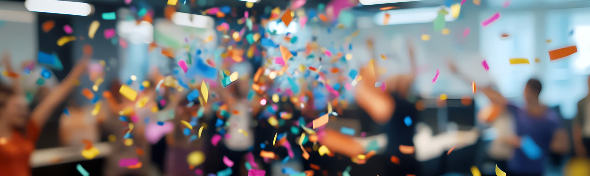 Confetti in various colours falling with a blurred office setting in the background.
