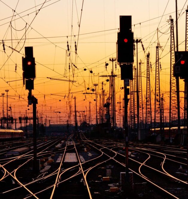 Railway signals in silhouette with a sunset background.