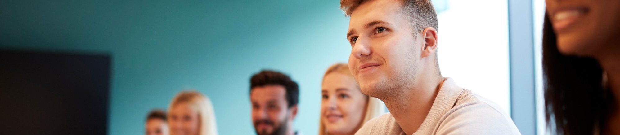People sit at a conference table taking notes during a meeting in a modern office room.