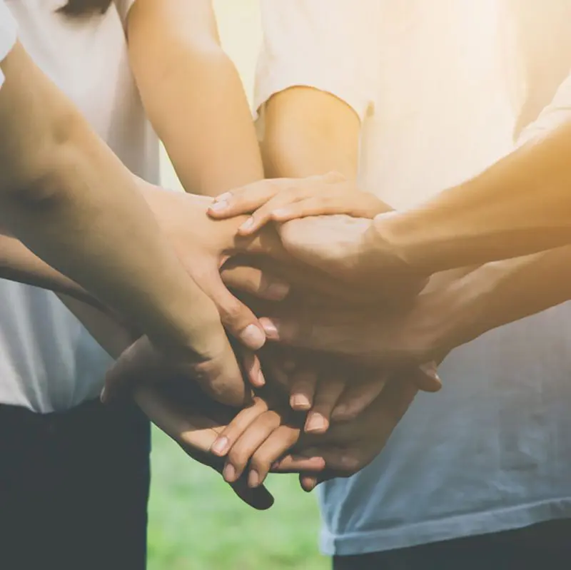 Multiple hands stacked together, representing teamwork, support and collaboration.